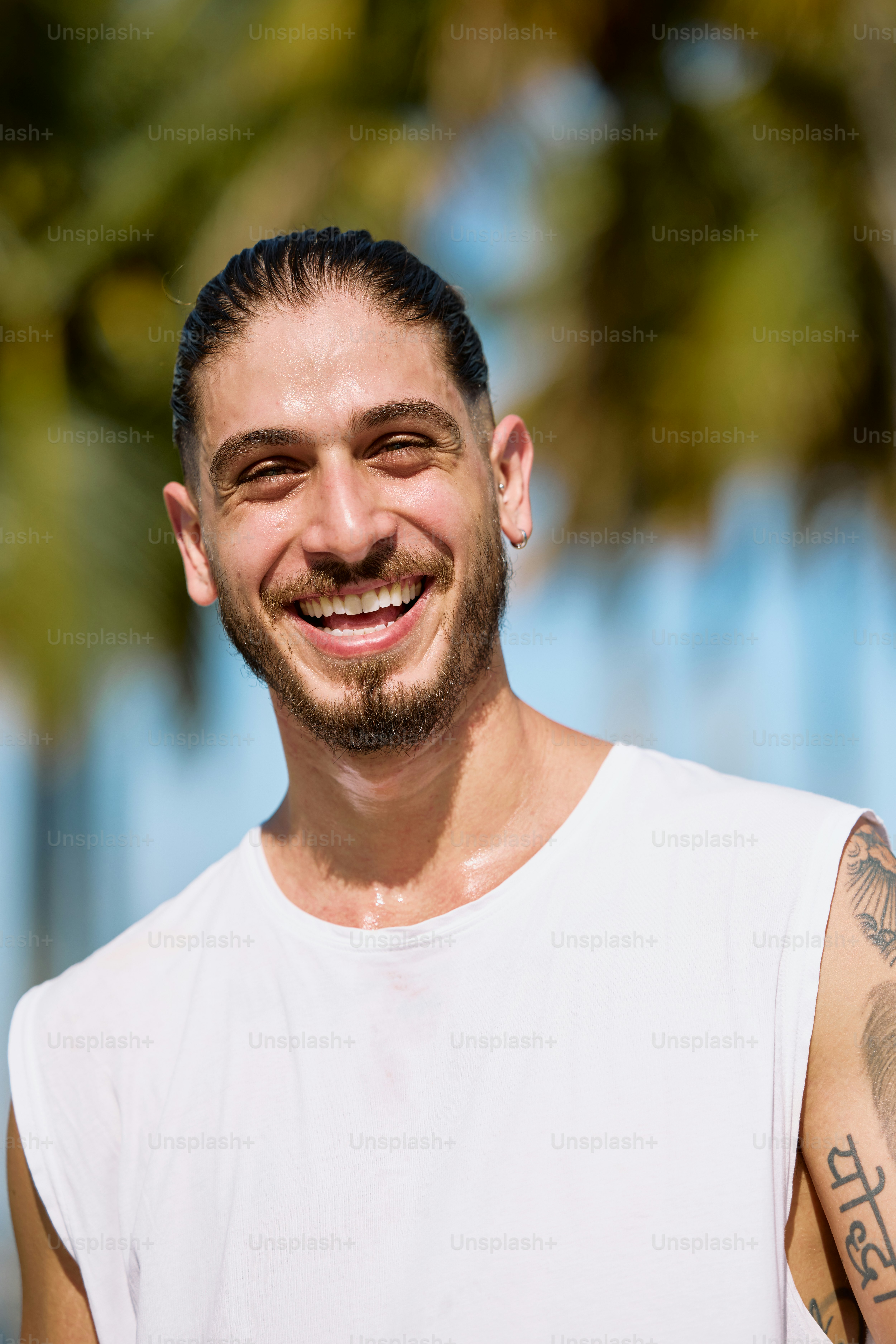 a man with a beard and tattoos smiling