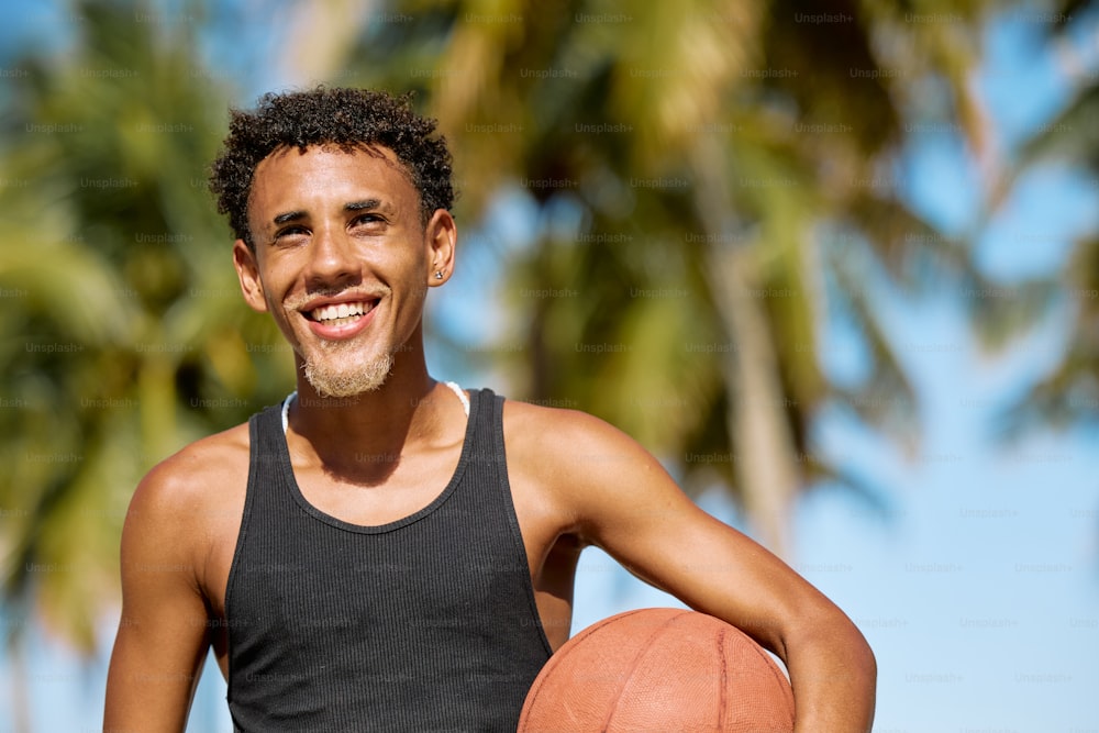 Un hombre sosteniendo una pelota de baloncesto frente a las palmeras
