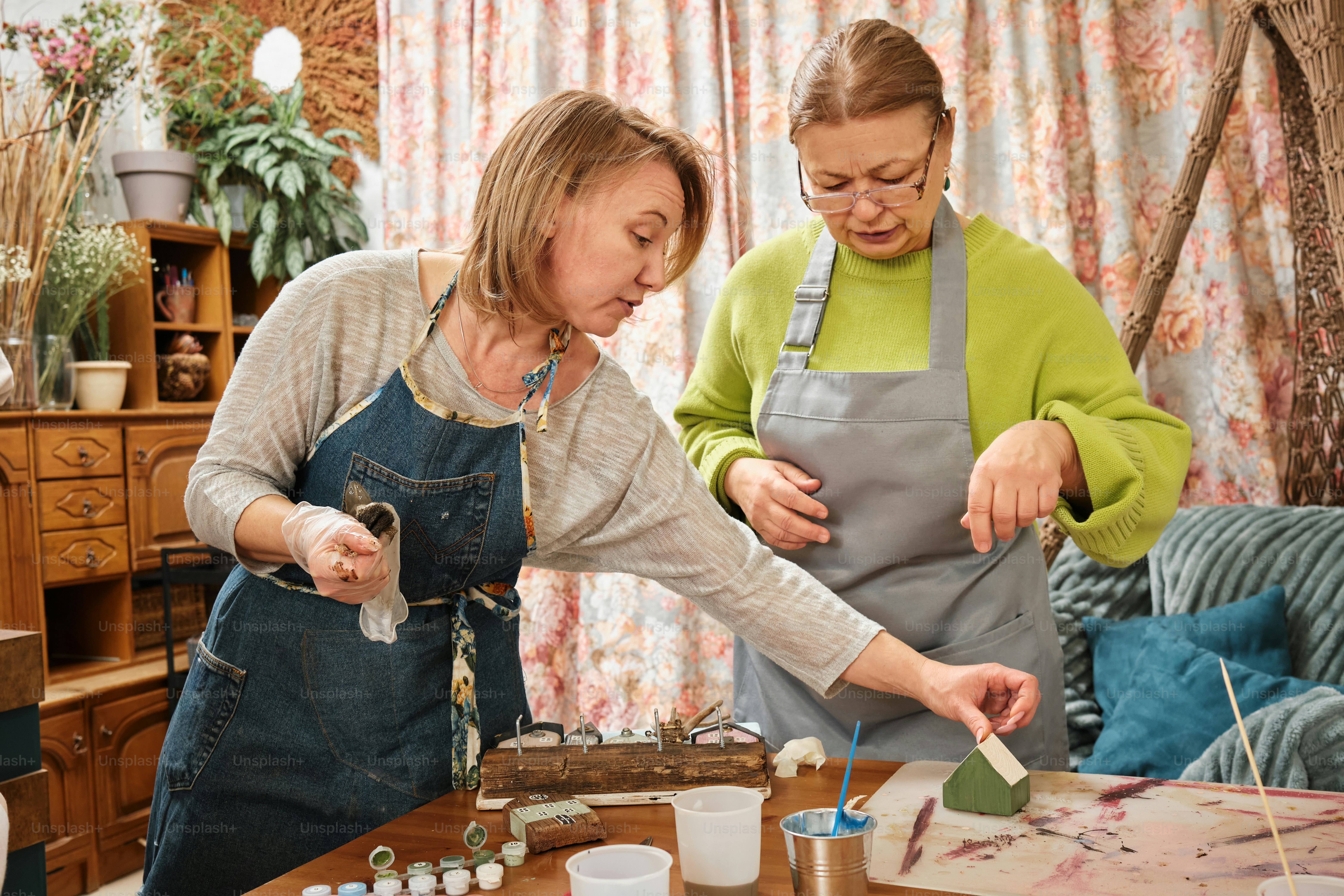 Two women in aprons working on a piece of wood photo – Community Image ...