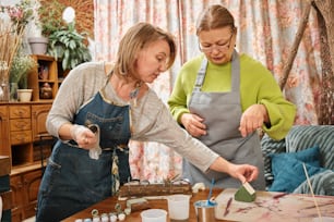 two women in aprons working on a piece of wood