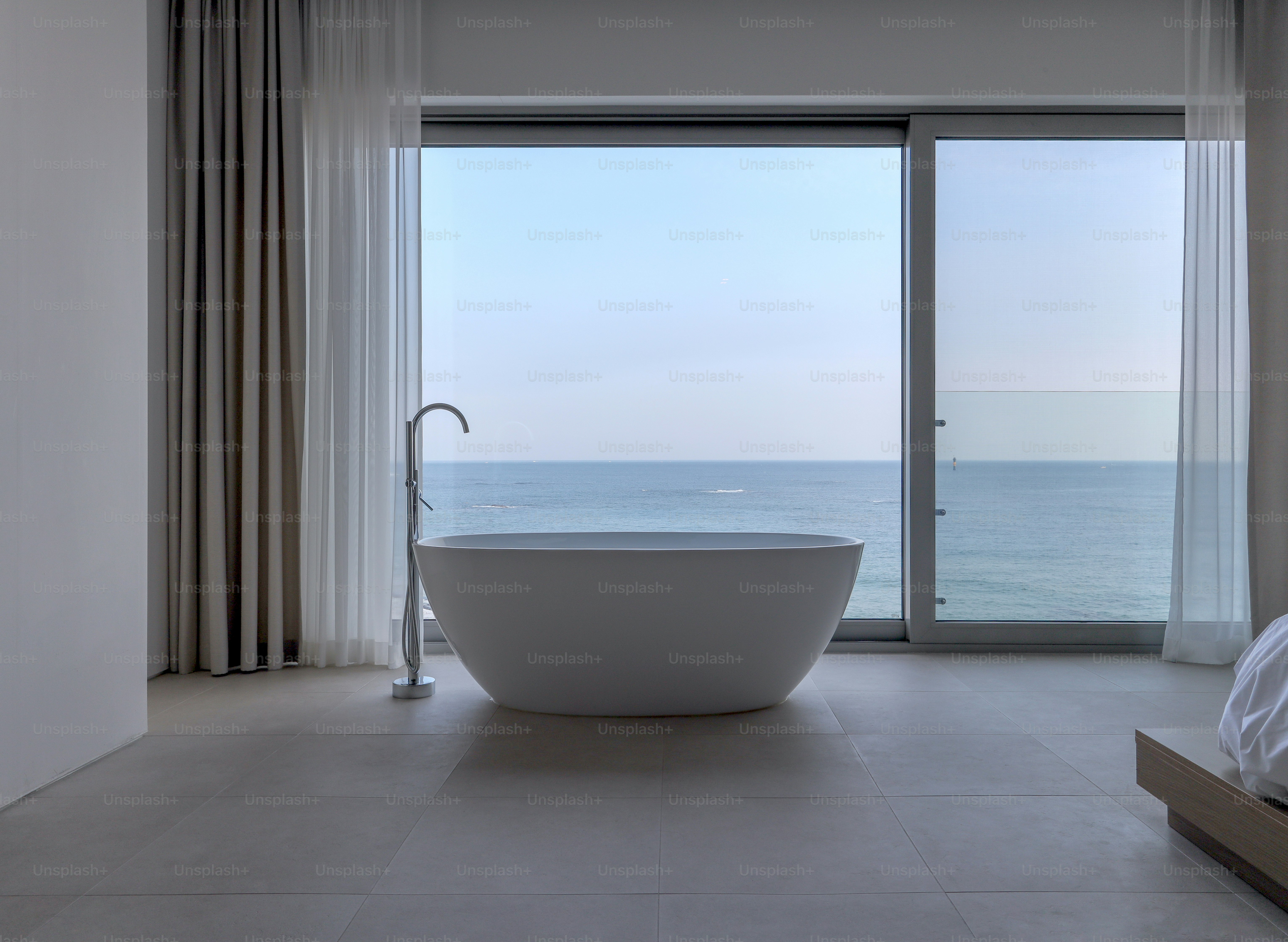 una grande vasca da bagno seduta in un bagno accanto a una finestra