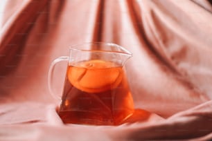 a pitcher of tea with an orange in it
