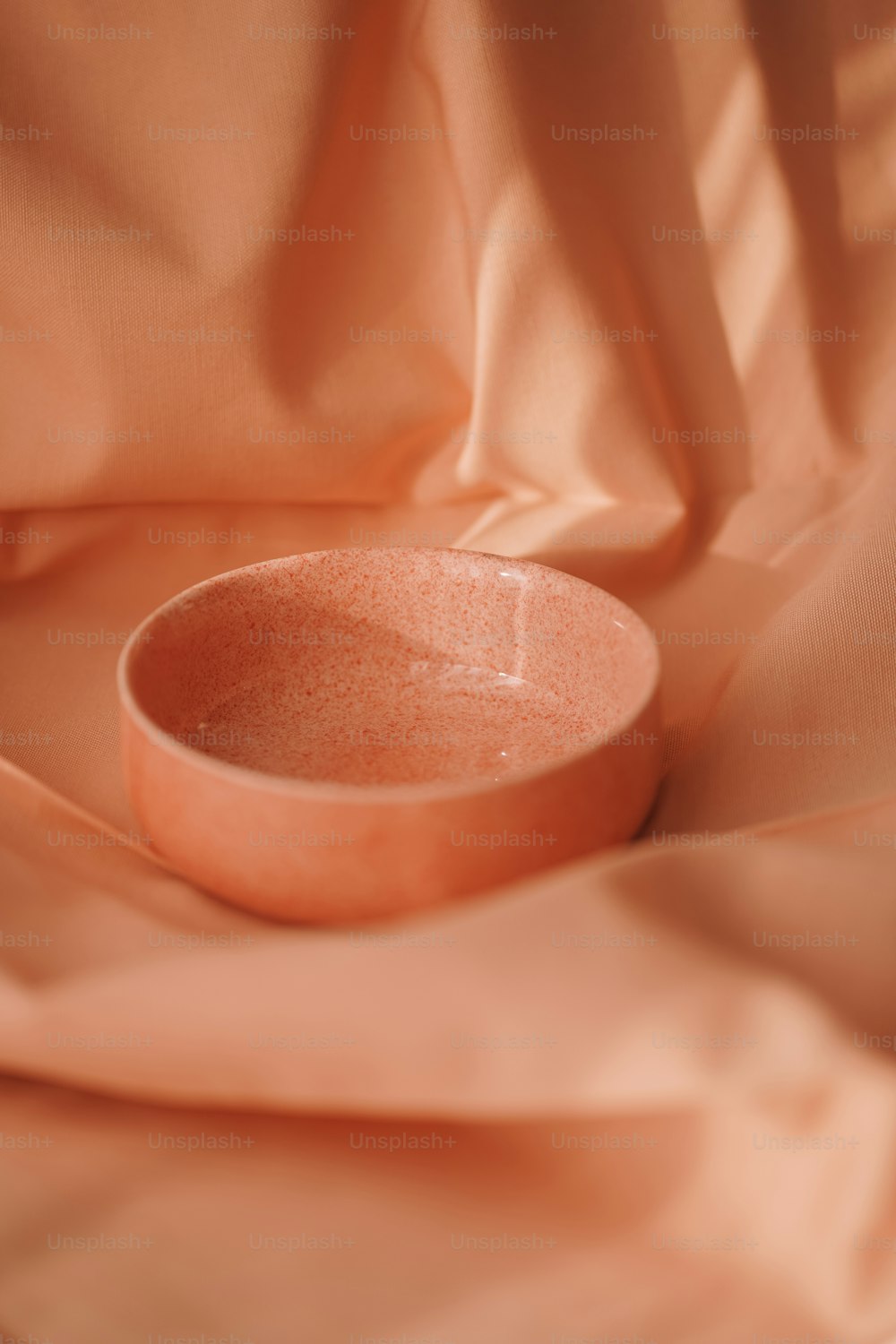 eine rosa Schale, die auf einem rosa Tuch sitzt