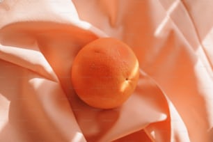 un'arancia seduta sopra un panno rosa