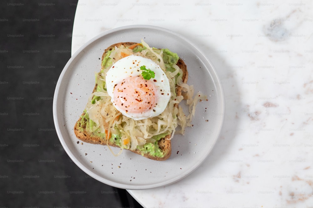 a white plate topped with an egg on top of a toast