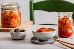 a table topped with a bowl of food next to a jar of pickles