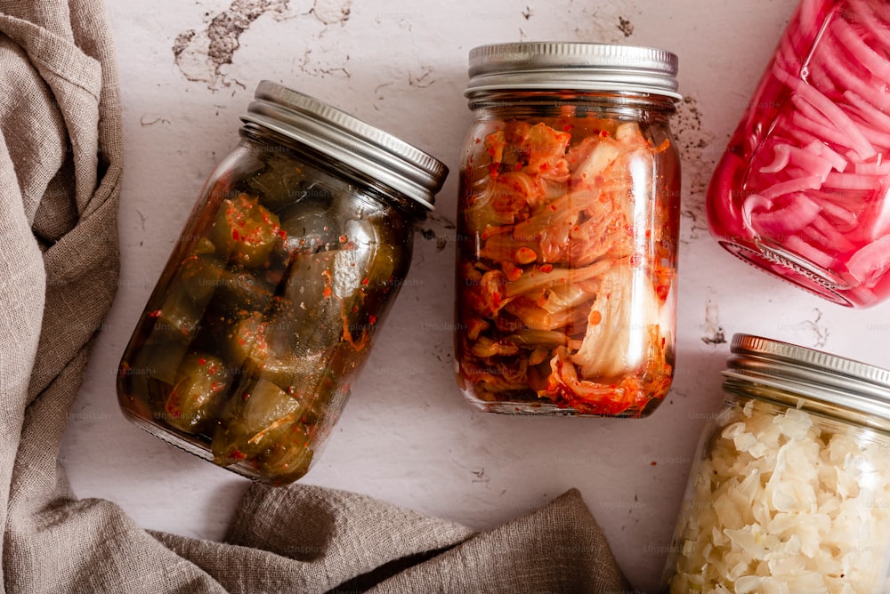 three jars of pickles and onions on a table