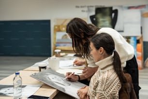 zwei Frauen sitzen an einem Tisch und arbeiten an einem Blatt Papier