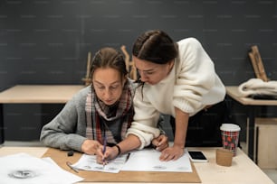 two women looking at a piece of paper on a table