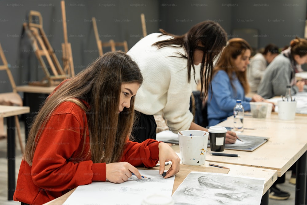 Eine Gruppe von Frauen sitzt an einem Tisch und arbeitet an Zeichnungen