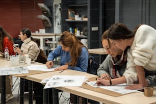 a group of people sitting at a table working on drawings