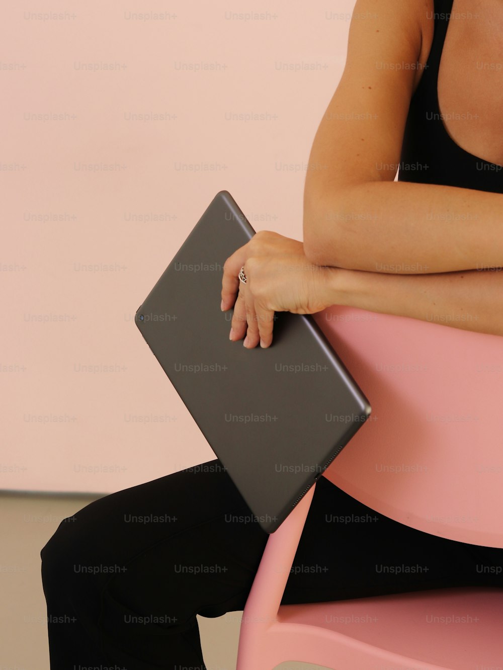 a woman sitting on a pink chair with a laptop