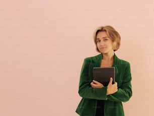 Una donna in una giacca verde tiene in mano un tablet