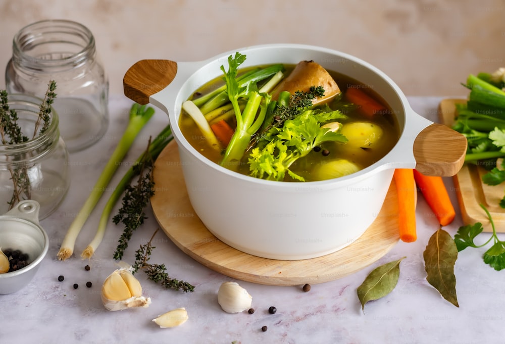 a bowl of soup with broccoli, carrots, celery,