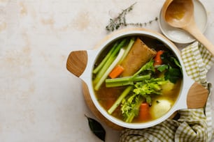a bowl of soup with broccoli, carrots, celery and