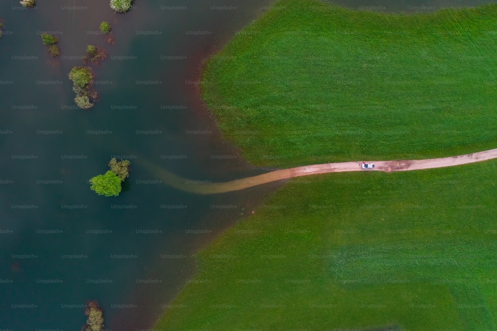 an aerial view of a river running through a lush green field
