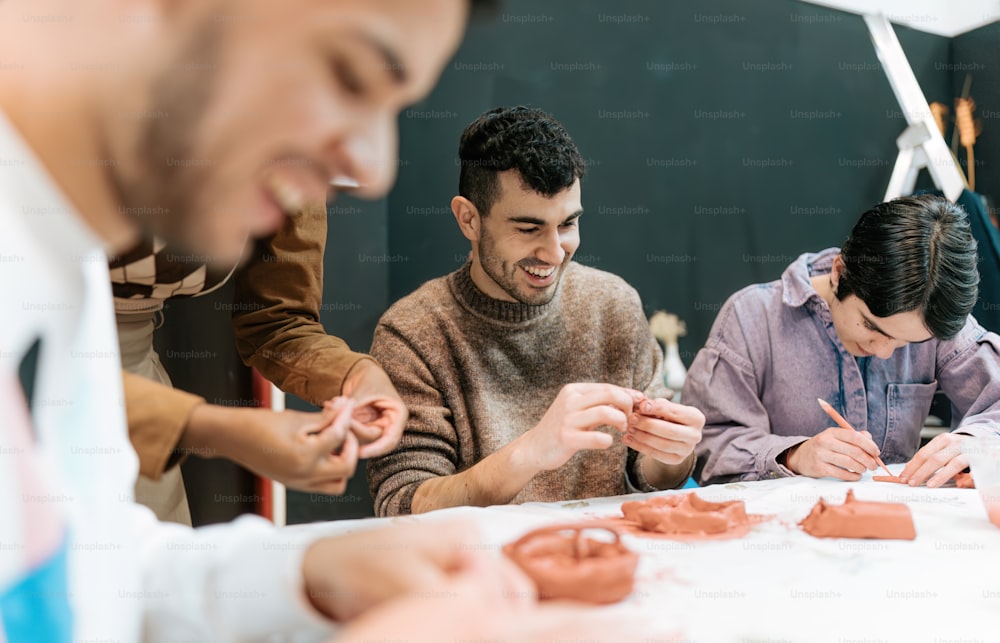 a group of people sitting around a table working on clay
