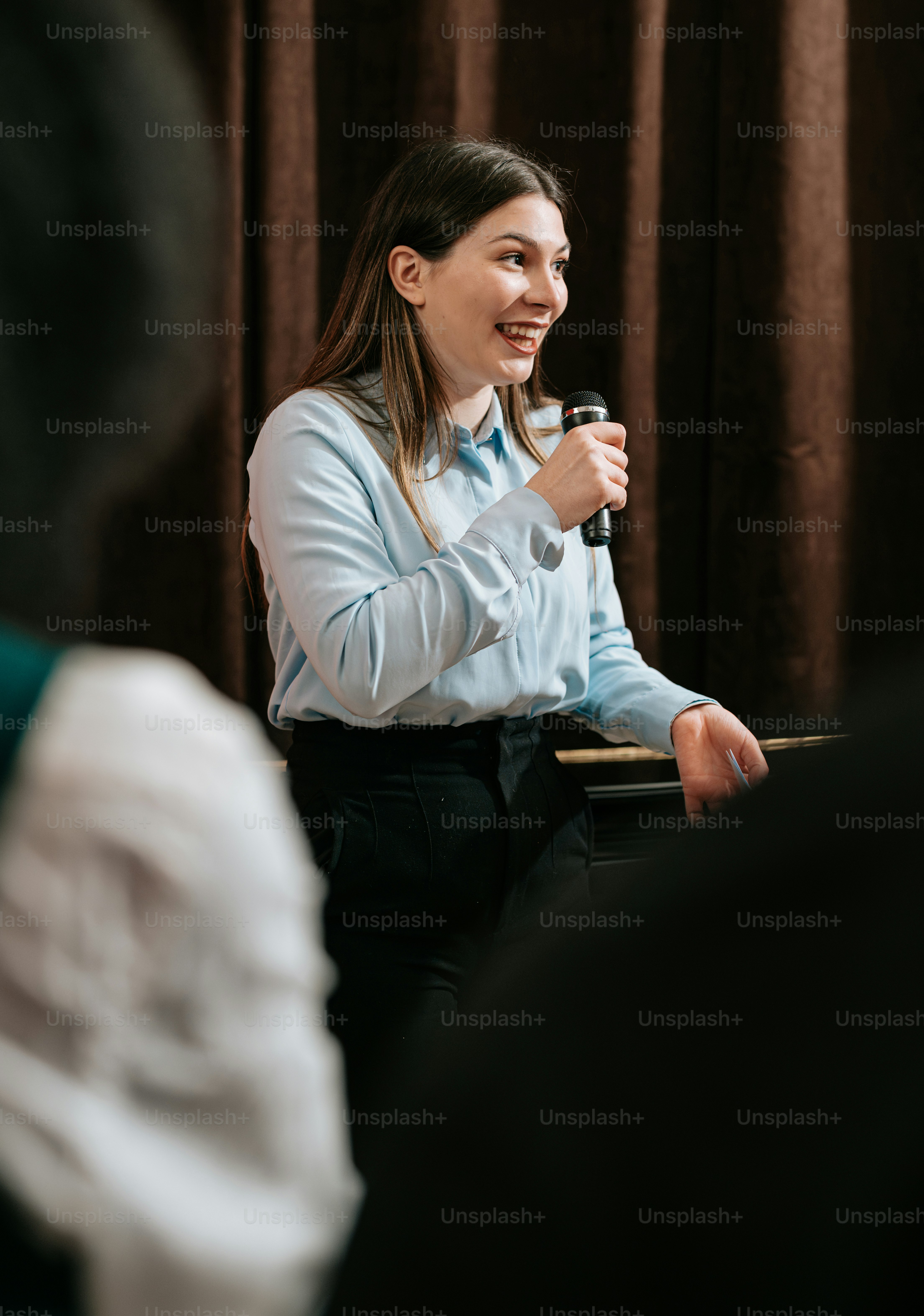 a woman speaking into a microphone in front of a curtain