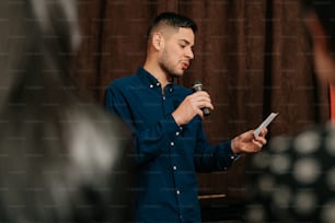 a man standing in front of a microphone holding a piece of paper