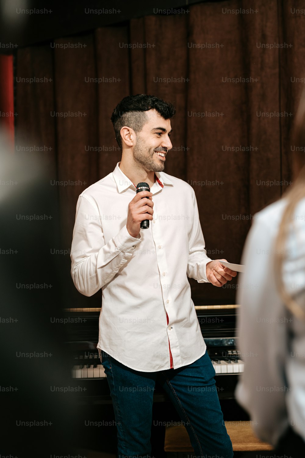 a man standing in front of a piano holding a microphone