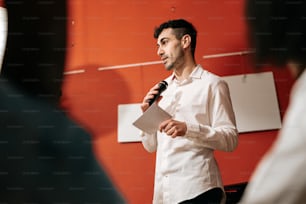 a man standing in front of a microphone holding a piece of paper