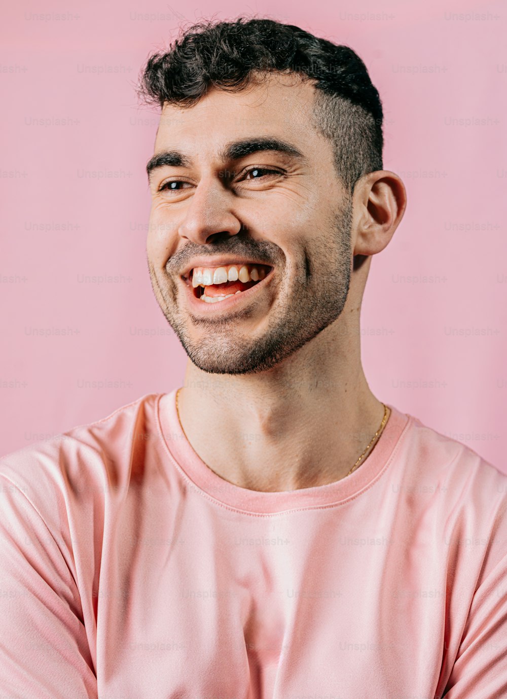 ピンクのシャツを着て腕を組んで微笑む男性