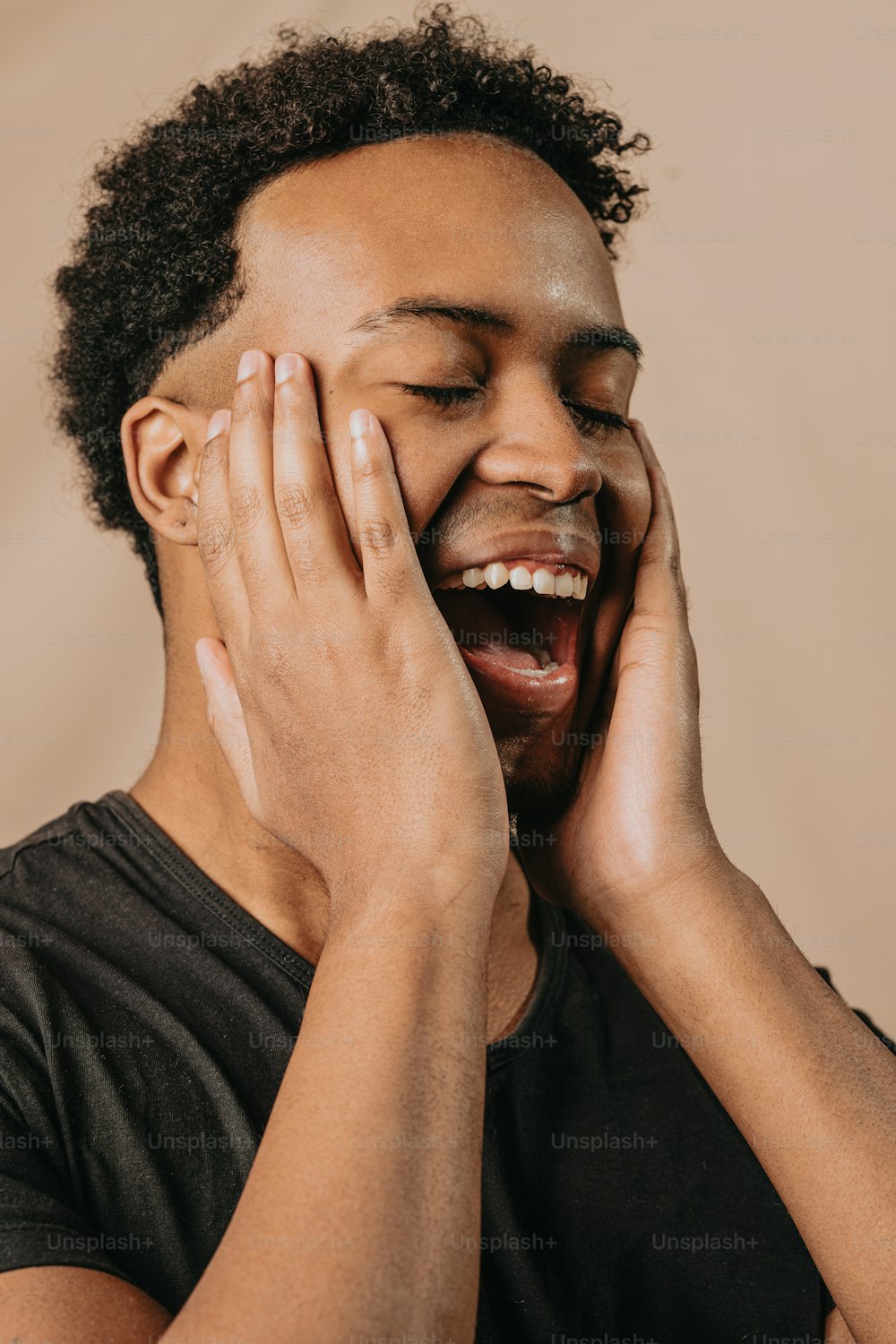 a man laughing while holding his hands to his face