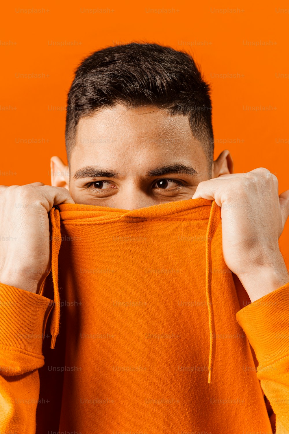 a young man holding up a hoodie over his face