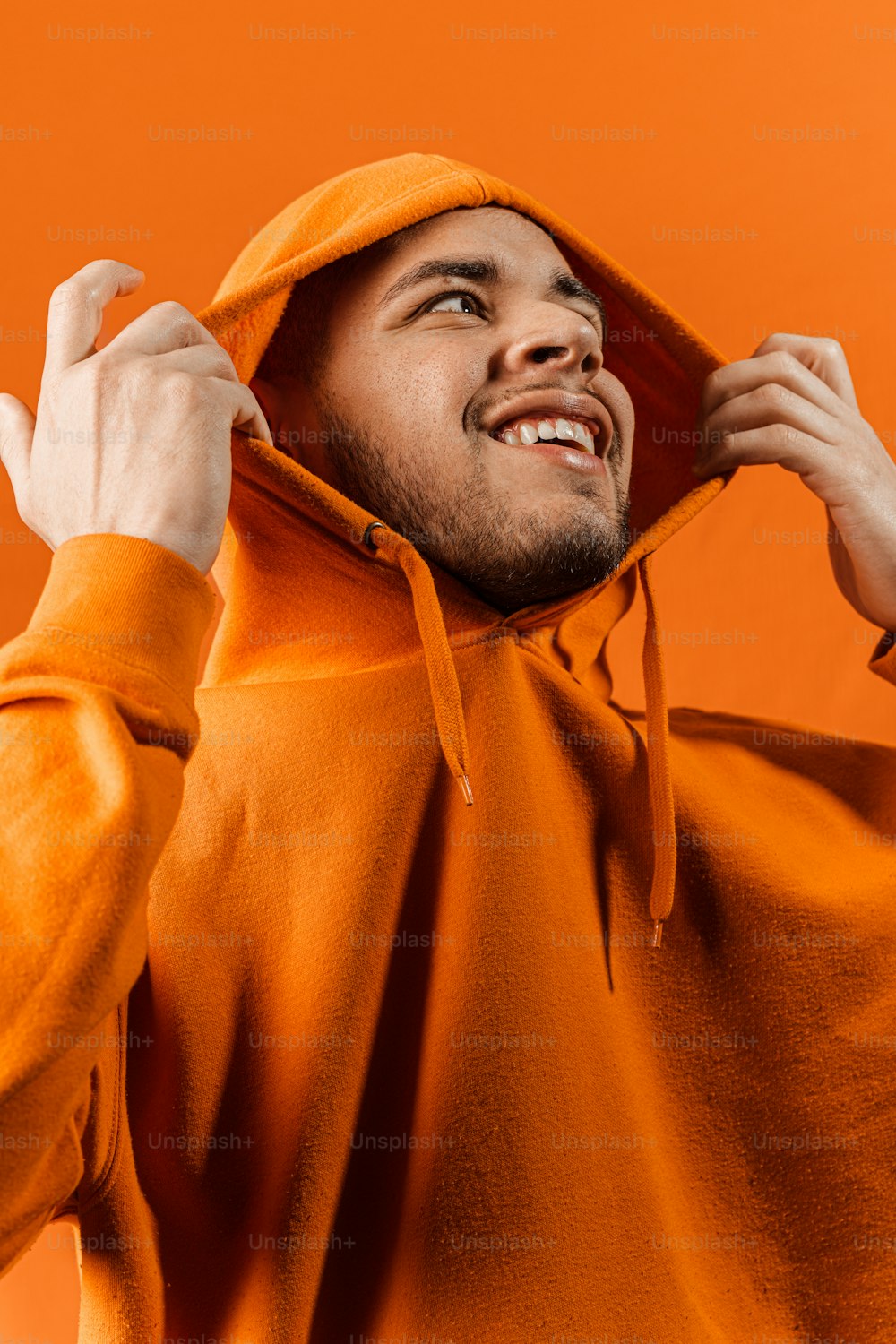 Um homem com um capuz laranja está sorrindo
