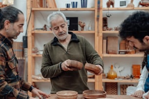 three men working on pottery in a pottery studio