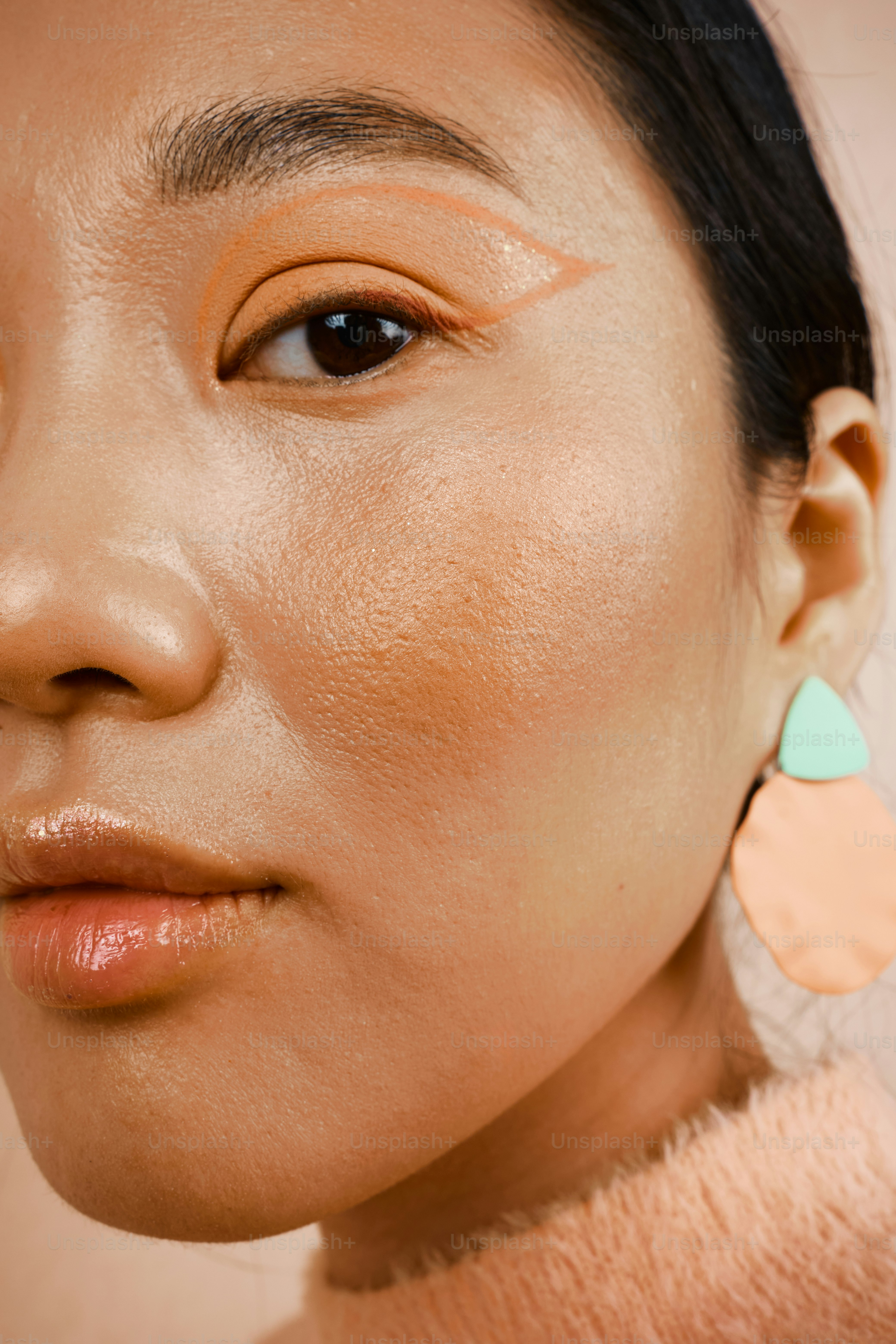 a beautiful asian woman with peach trendy makeup on the peach colored background