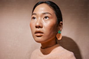 a woman wearing a pink sweater and green earrings