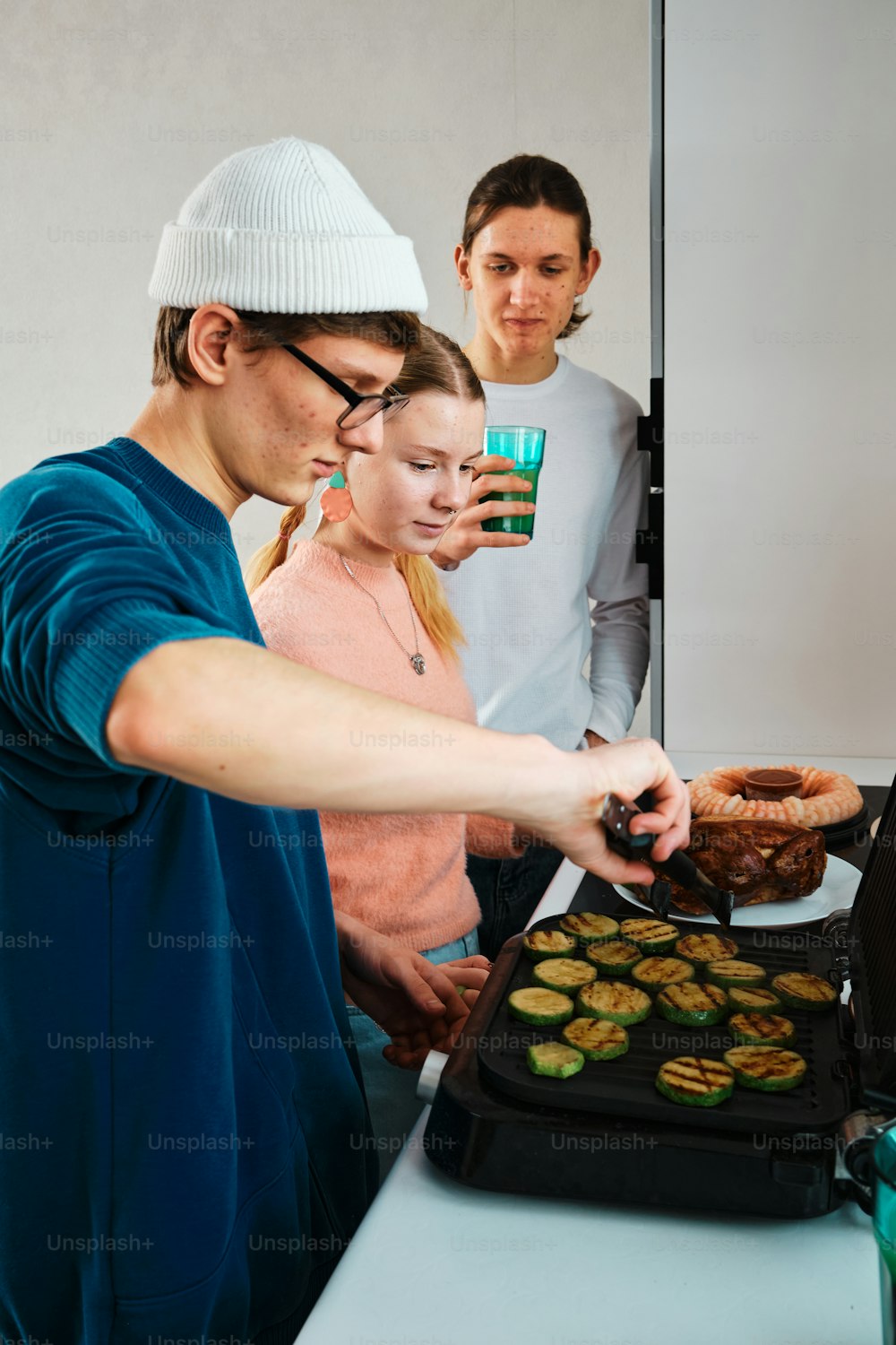 a group of people standing around a pan of food