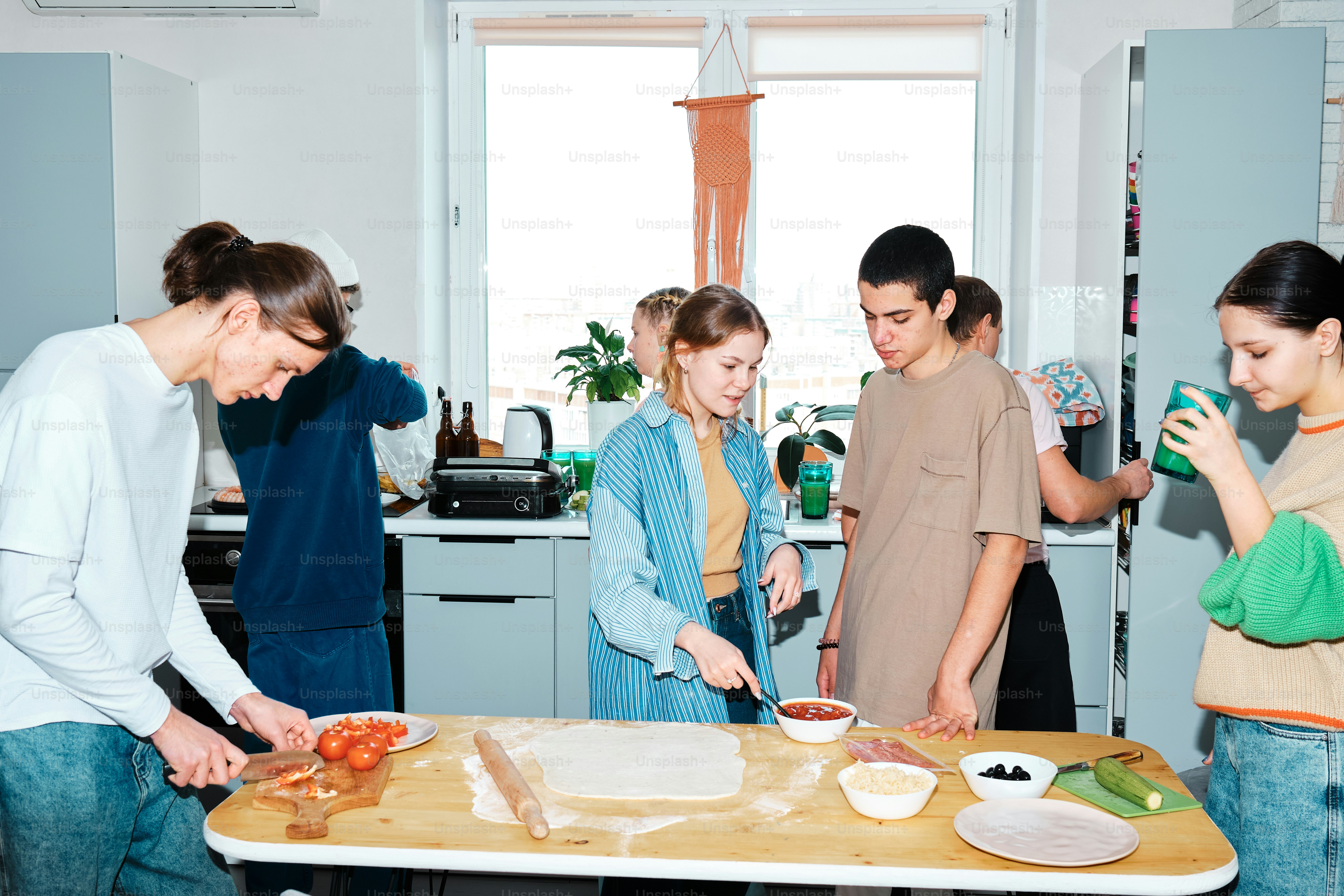 Eine Gruppe von Menschen, die um einen Tisch herum stehen und Essen zubereiten
