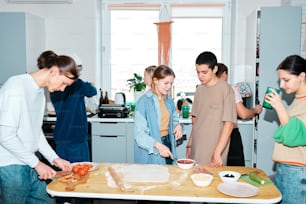 a group of people standing around a table preparing food