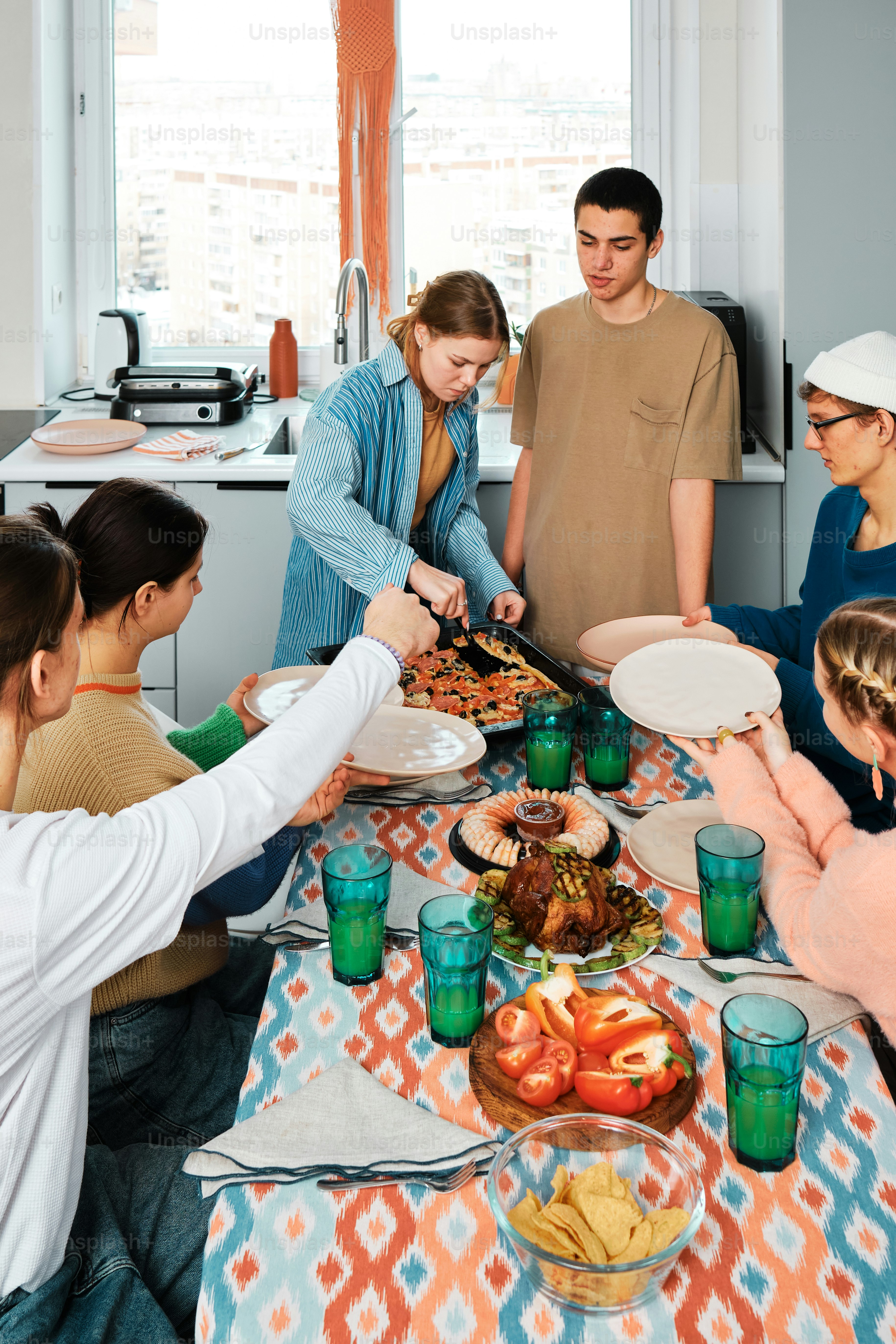 A group of people standing around a table with plates of food photo ...