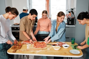 a group of people standing around a table preparing food