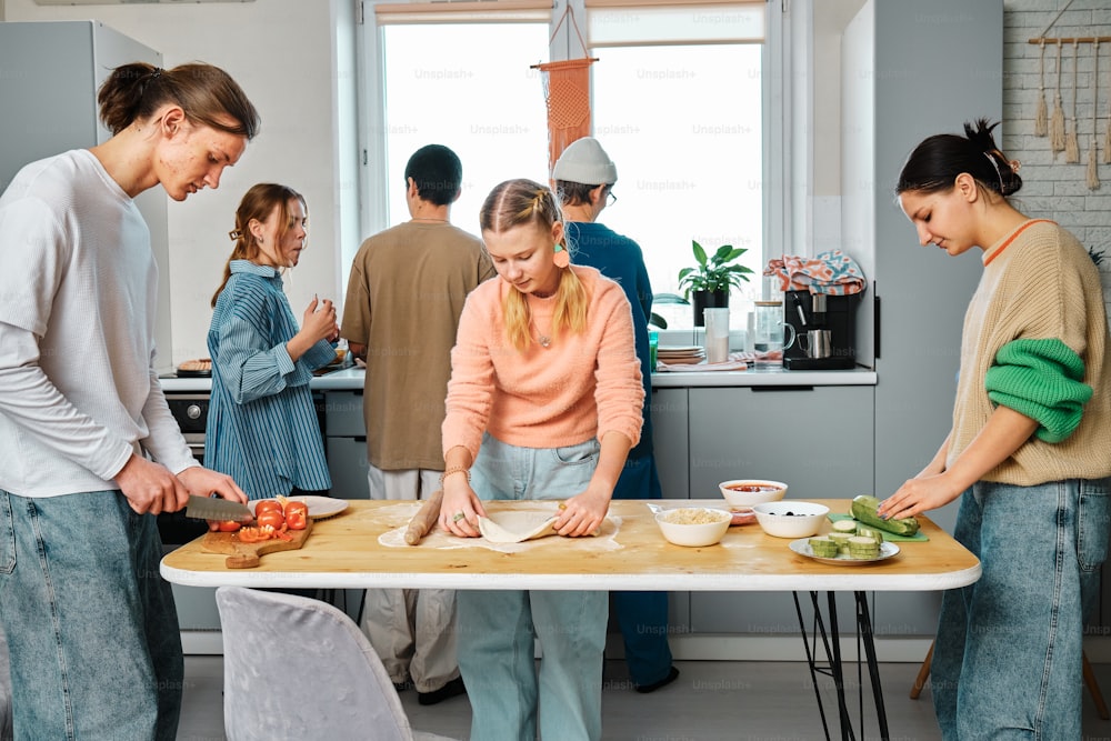 a group of people standing around a table preparing food