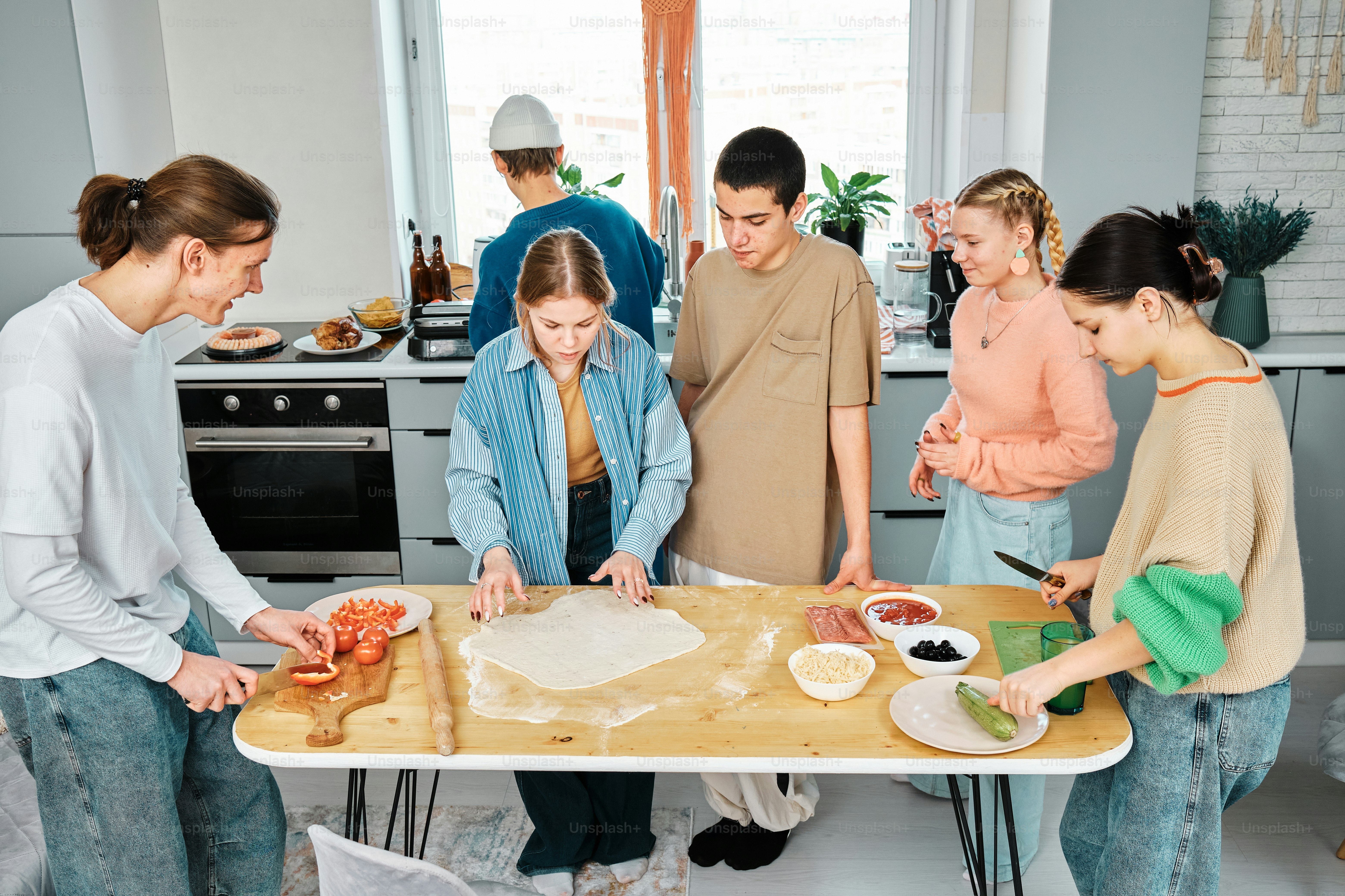 A group of people standing around a table preparing food photo ...