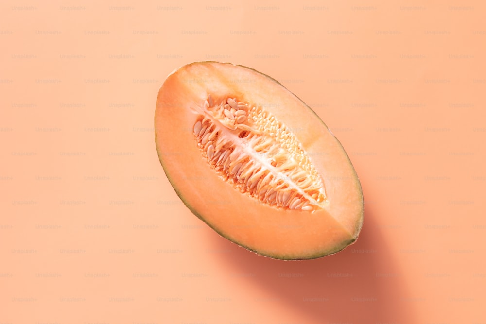 a melon cut in half on a pink background