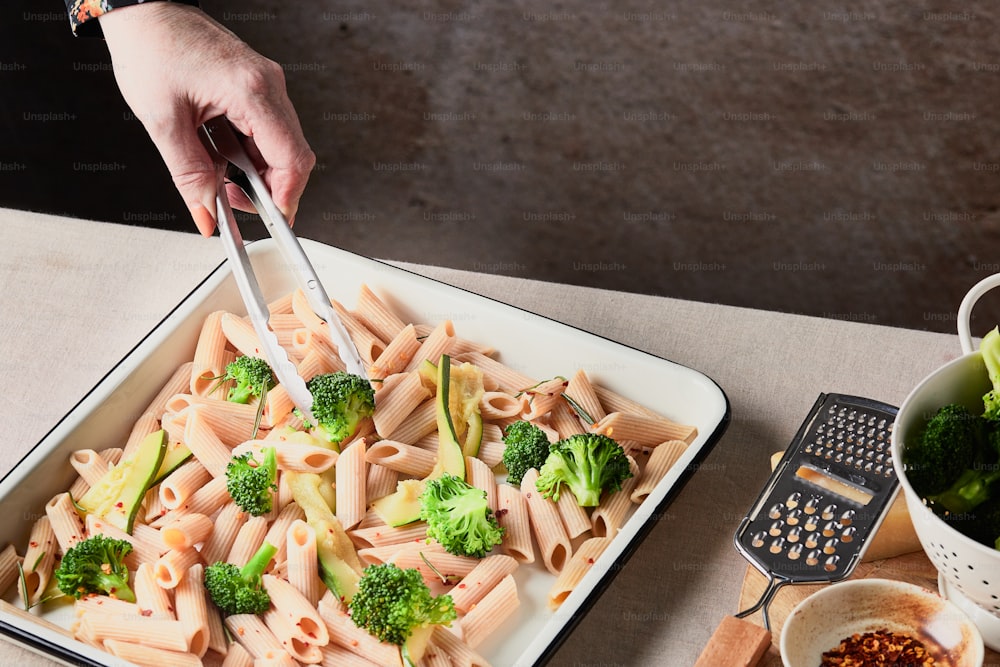 un piatto di pasta con i broccoli e una grattugia
