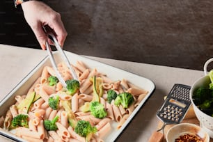 un plato de pasta con brócoli y un rallador