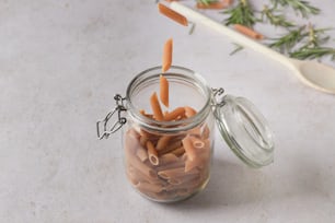 a glass jar filled with carrots on top of a table