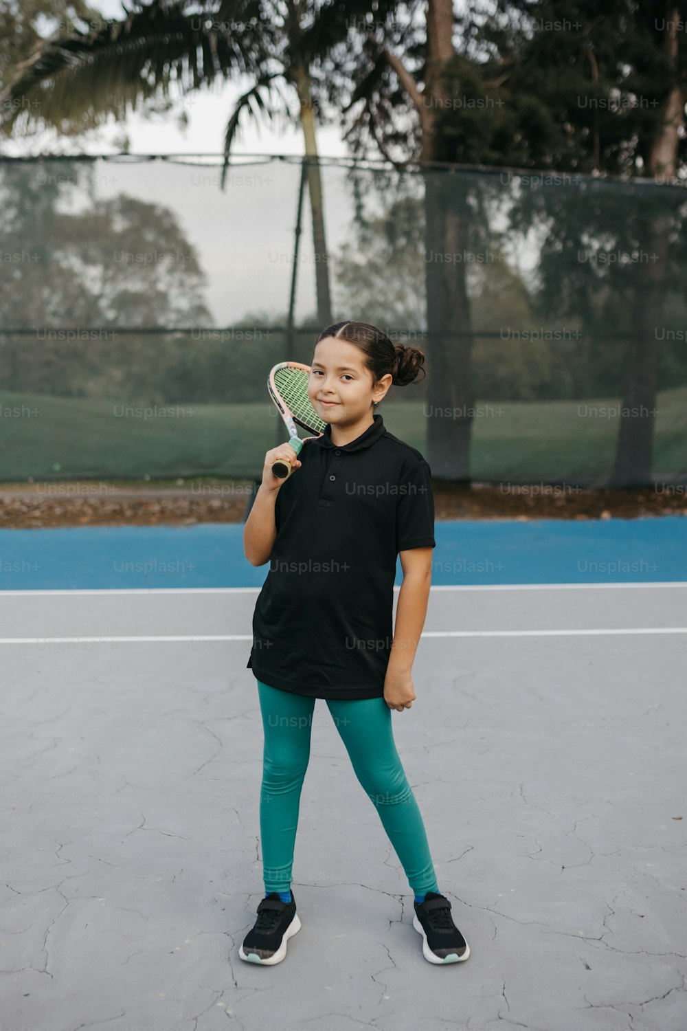 a young girl holding a tennis racquet on a tennis court