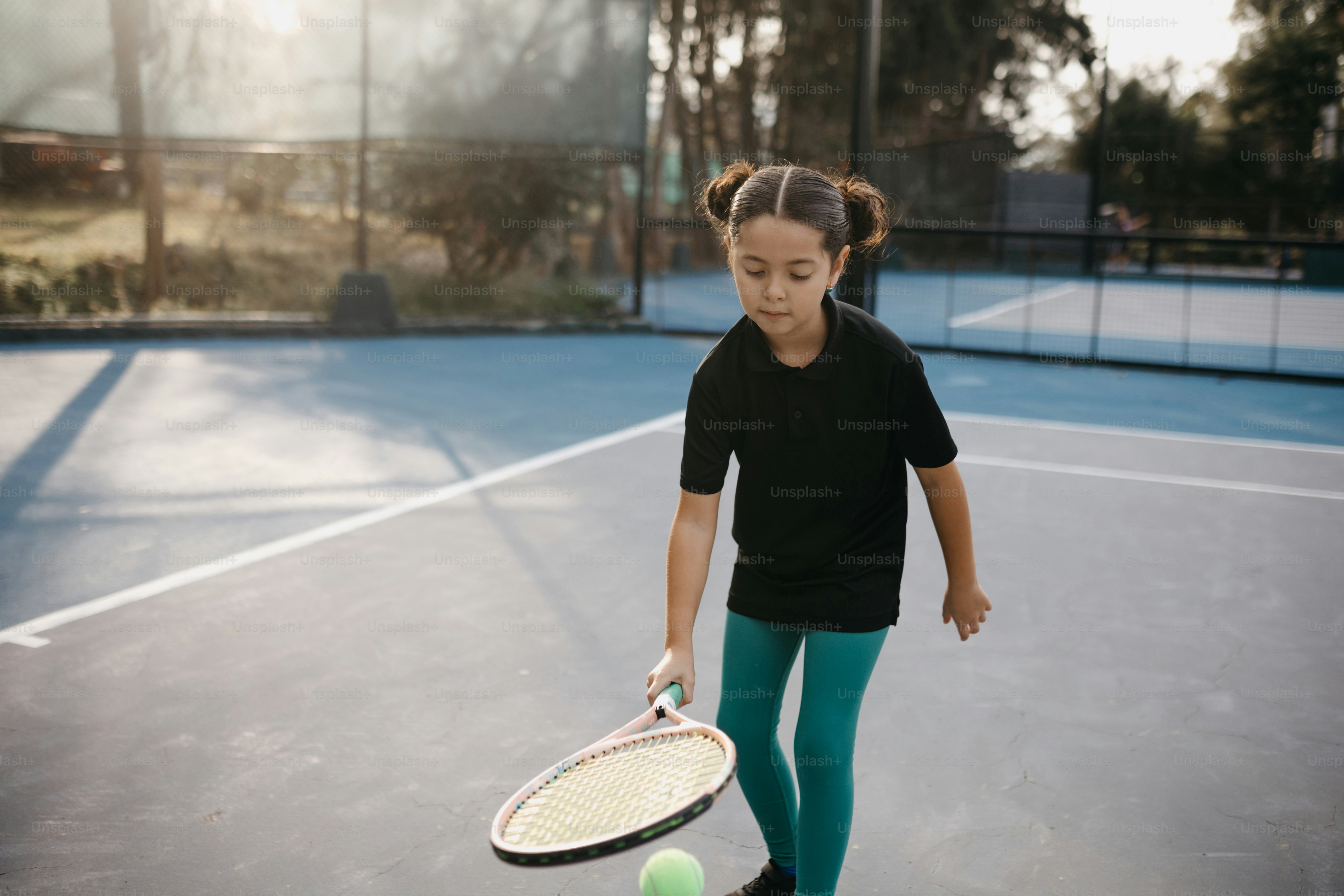 A young girl holding a tennis racquet on a tennis court photo – Tweens ...