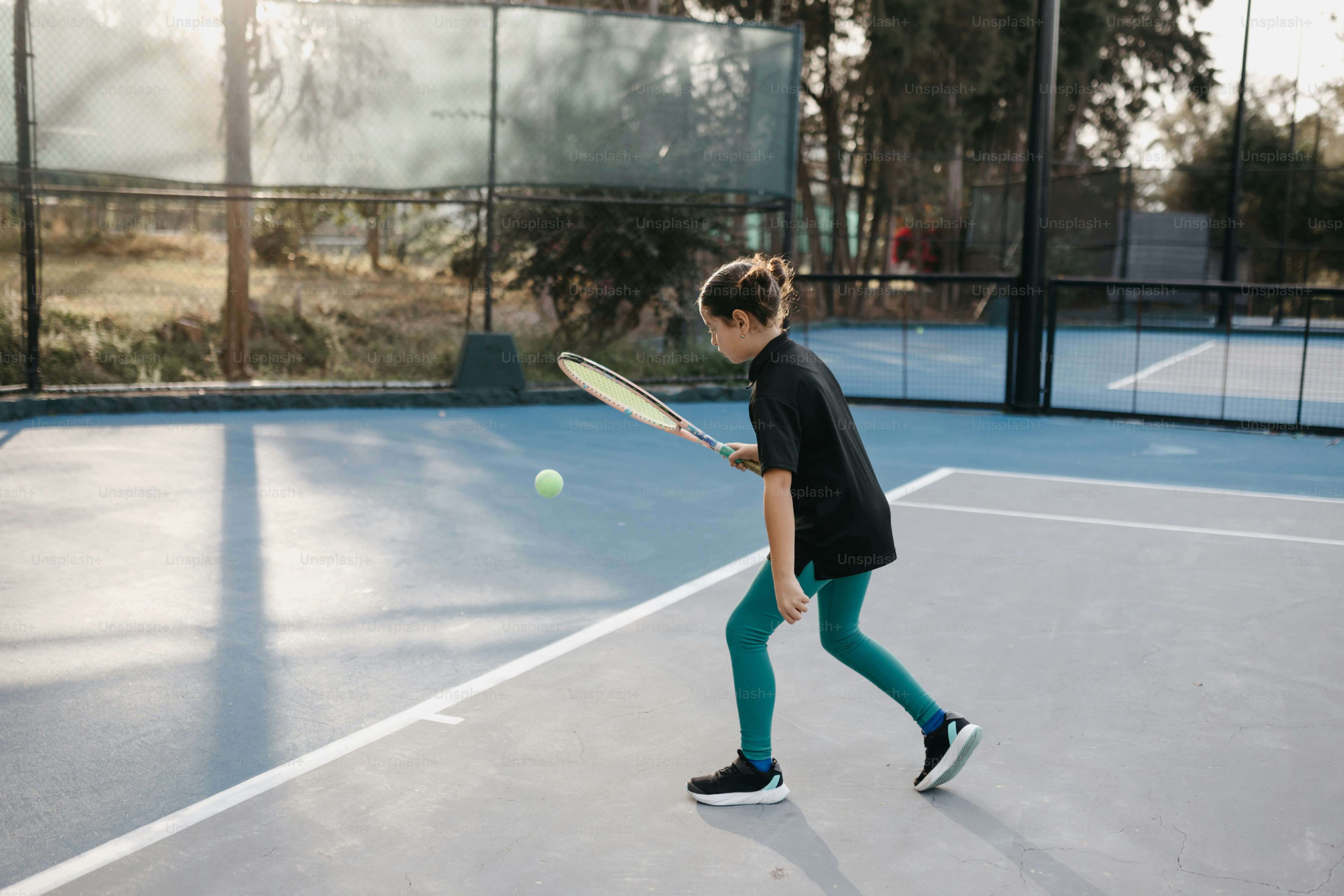 a young boy holding a tennis racquet on top of a tennis court