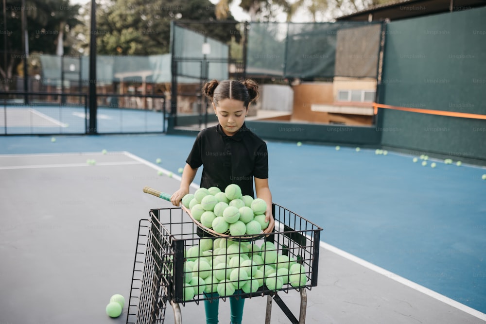 a young girl holding a basket full of tennis balls
