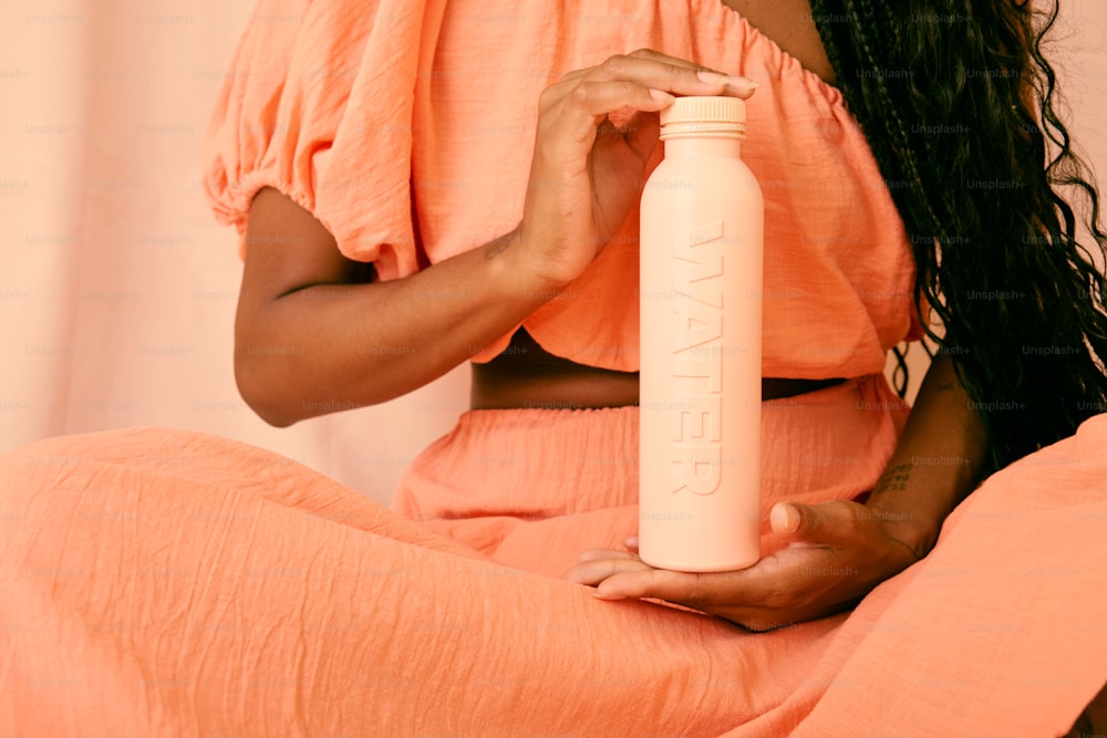 una mujer sentada en una cama sosteniendo una botella de agua