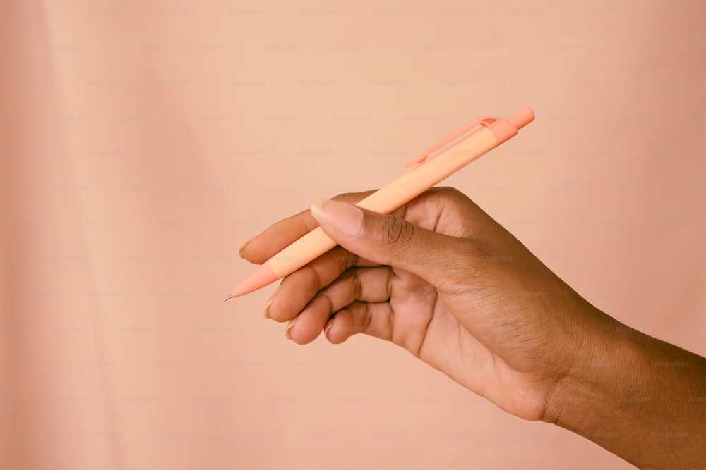 a hand holding a pink and orange toothbrush