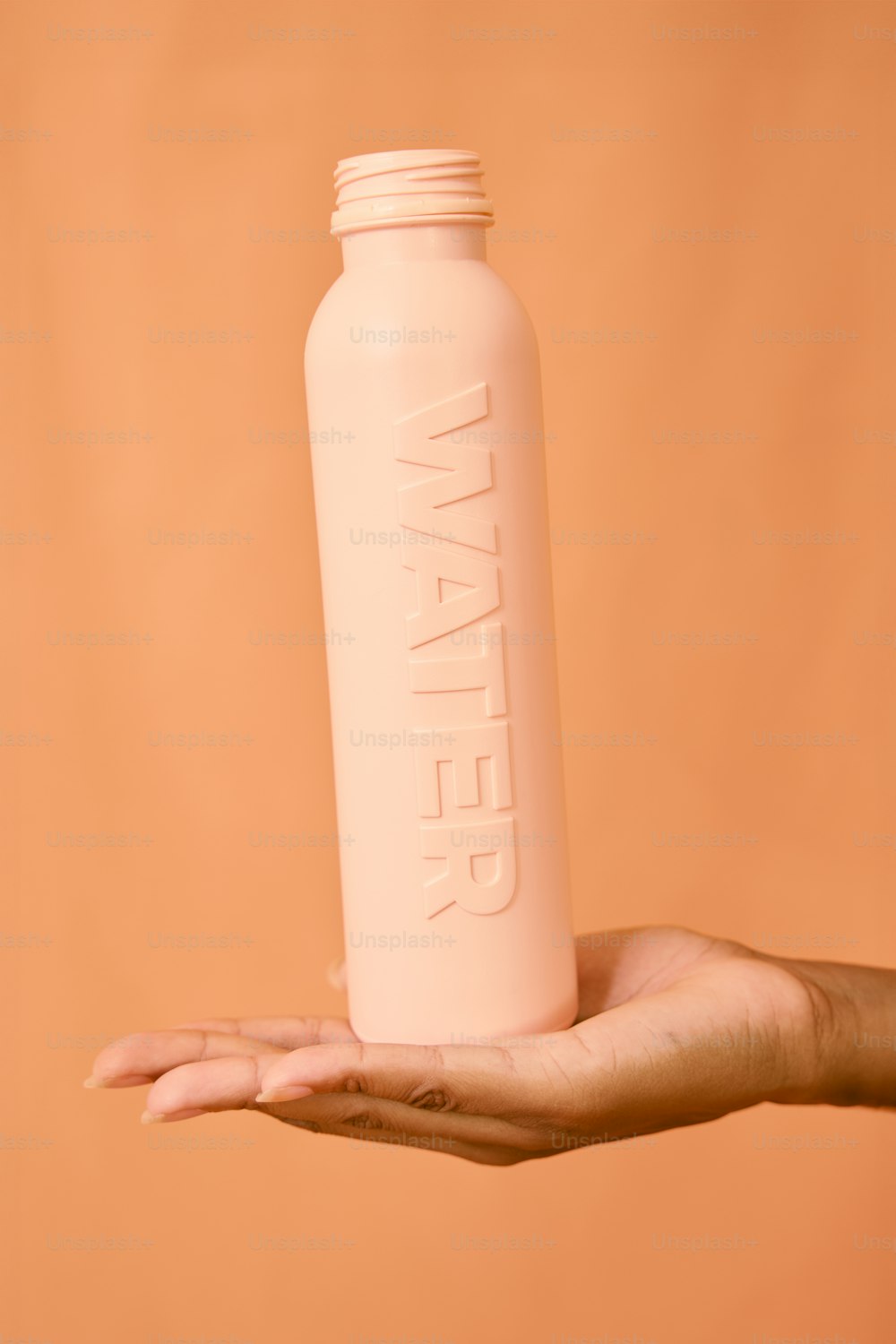 una persona sosteniendo una botella de agua rosa en la mano